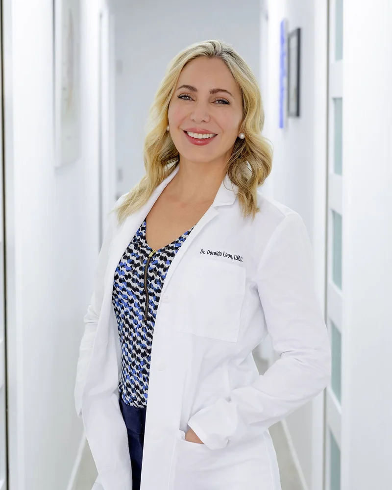 Dr. Leon smiling in her white coat in the office hallway
