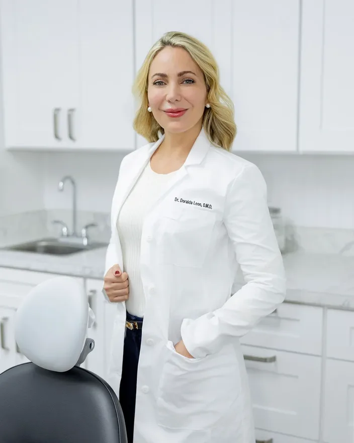 La Dra. Leon con su bata blanca junto al sillón de tratamiento